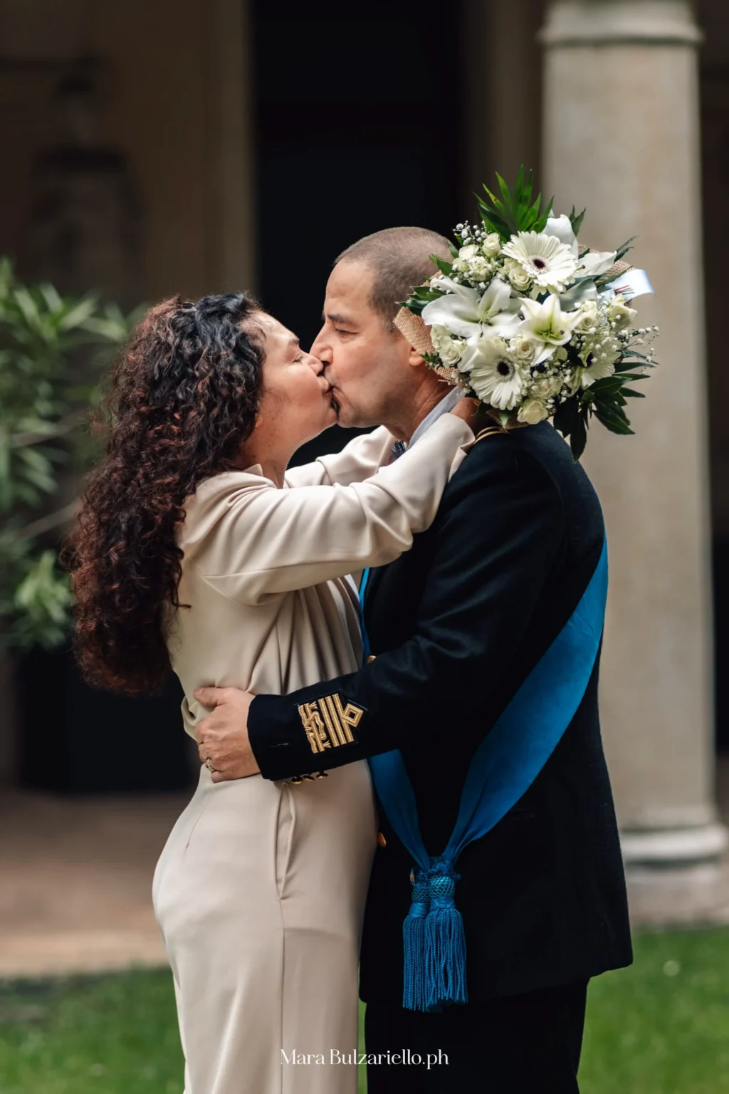 Bacio degli sposi con bouquet durante il matrimonio